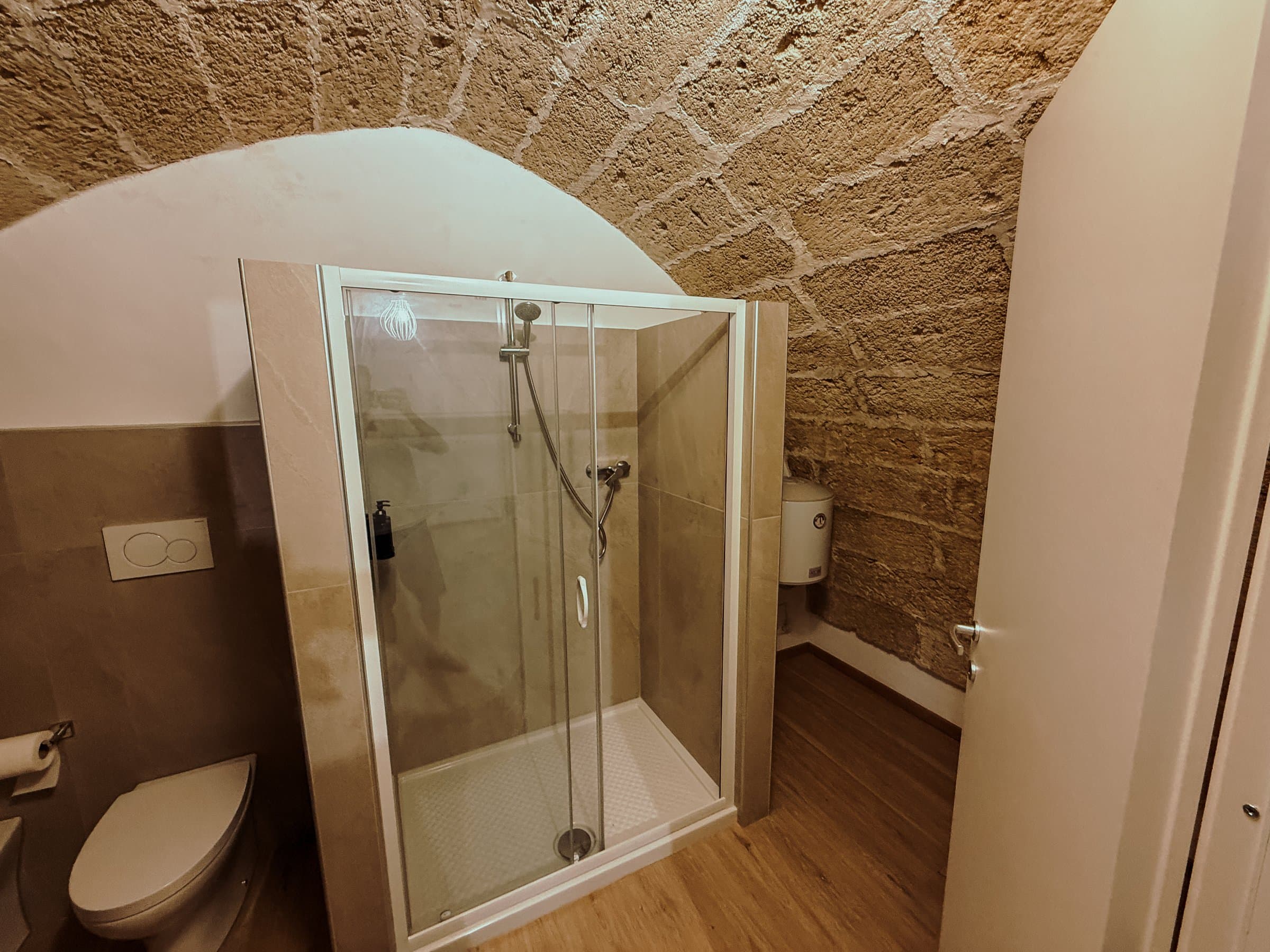 Bagno con doccia e parete in pietra a vista
